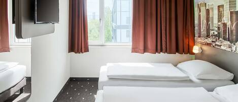 Habitación de hotel con dos camas, un televisor de pantalla plana montado en la pared y una ventana con cortinas marrones.