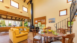 Un vaste espace de vie comprenant un canapé, une table à manger, des chaises, une cheminée et un escalier.