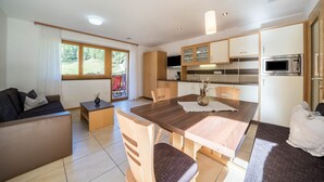 Un salon moderne comprenant un canapé, une table à manger et un coin cuisine avec des placards et un four à micro-ondes.