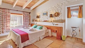 A bedroom with a bed, bedside tables, a dresser, a mirror, and a window with curtains. - "Ca les Estamenyes" near the sea, Wi-Fi, air conditioning, garden and pool (POLLENÇA)