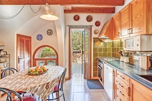 Una cocina con armarios de madera, una mesa de comedor con sillas, un microondas y una estufa.