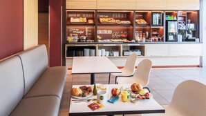 A breakfast area with seating, a buffet with various food items, and a coffee machine.