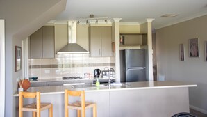 A modern kitchen with a central island, stainless steel appliances, and light-colored cabinetry.