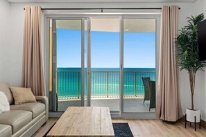 Una habitación con puerta corrediza de vidrio que da a un balcón con vista al océano.