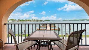 A balcony with a table and chairs overlooking a marina with boats and a dock. - Bay Time - Waterfront - Walk to beach and restaurants - Dock your boat (Englewood)
