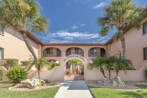 A building entrance with a sign reading "EL GALEON EAST," surrounded by palm trees and a clear sky.