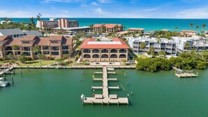 A marina with docked boats, a central building with arched windows, and a view of the ocean. - Bay Time - Waterfront - Walk to beach and restaurants - Dock your boat (Englewood)
