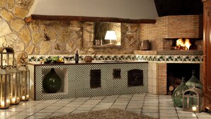 A rustic kitchen with a stone wall, a brick fireplace, and a checkered tile backsplash. - Stony Villa Volcano View (Massa Lubrense)