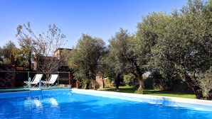A swimming pool with two white lounge chairs and a stone building in the background. - Stony Villa Volcano View (Massa Lubrense)