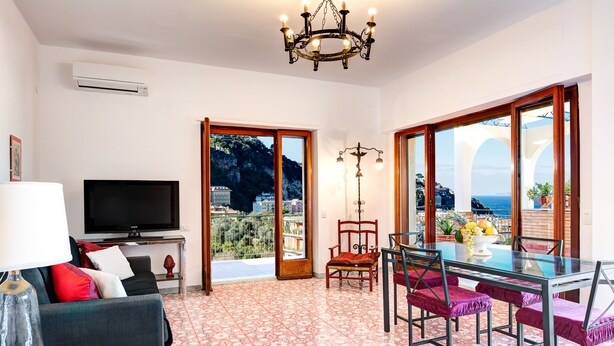 A living room with a TV, sofa, and a dining area with chairs and a table.