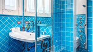 Une salle de bain avec un lavabo, un miroir et une douche aux carreaux bleus.
