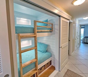 A bunk bed with a wooden ladder, a sliding door, and a small storage space under the bed.