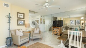 A spacious living room with a sofa, armchairs, a coffee table, and a dining area with a table and chairs.