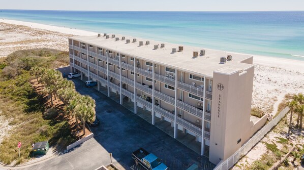 A multi-story hotel with balconies overlooking a beach.