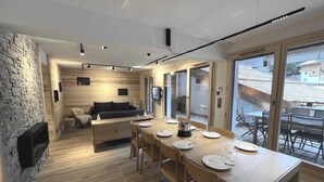 A modern kitchen with a wooden table set for dining, a stone wall, and a view of the outside. - BOREAL - Lovely apartment in the village center and close to the slopes - Wi-Fi - Garage (La Clusaz)