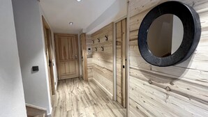 Un corridoio con pareti rivestite in legno, uno specchio circolare e una porta con maniglia.