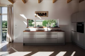 Una cocina moderna con un ventanal grande, encimera de madera y electrodomésticos integrados.