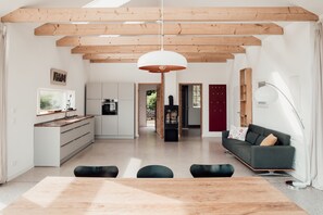 Amplia sala de estar con techo de madera, una mesa de comedor y un sofá.