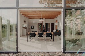 Un comedor moderno con techo de madera, una mesa grande y sillas negras.