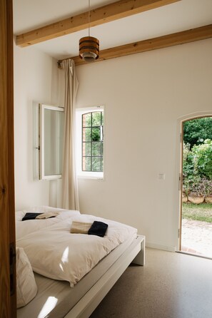 Un dormitorio con cama, ventana y vistas al exterior.