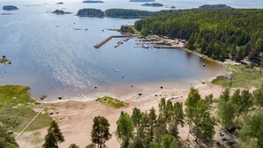 An aerial view of a coastal area with a marina, sandy beach, and dense forest.
