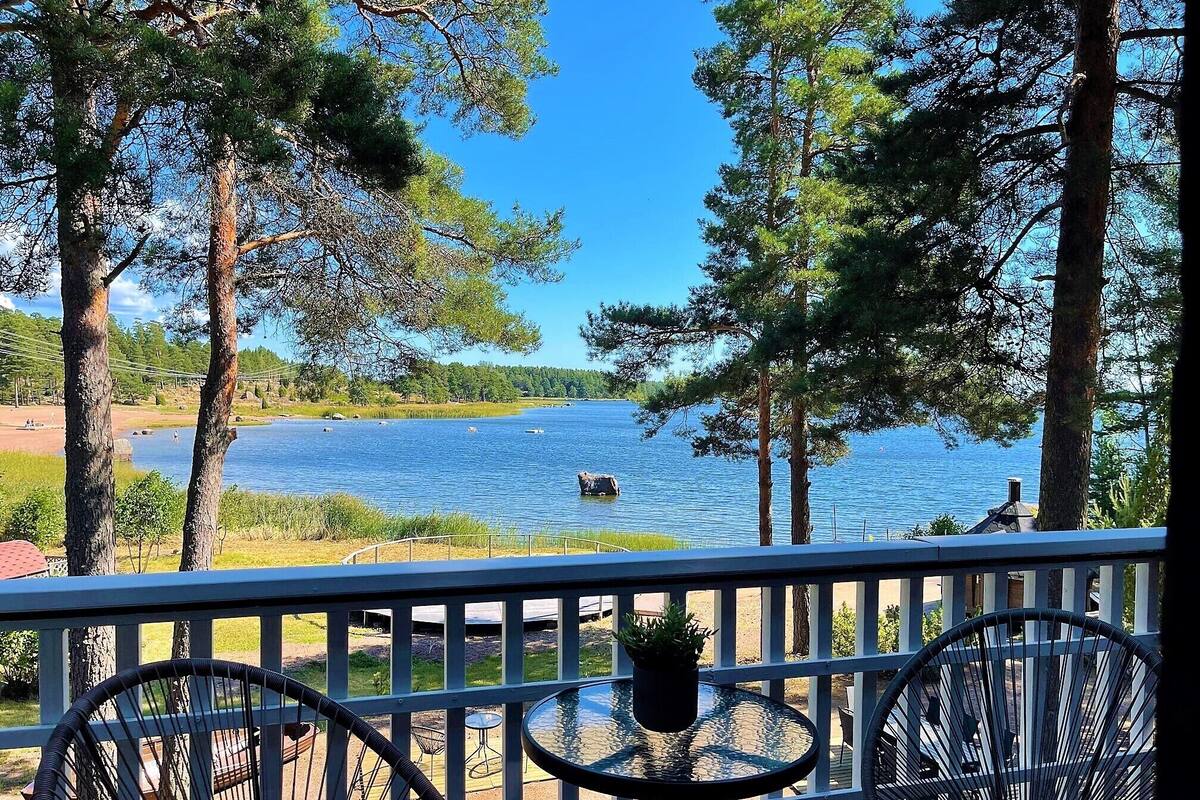 A balcony with a view of a lake, surrounded by trees.