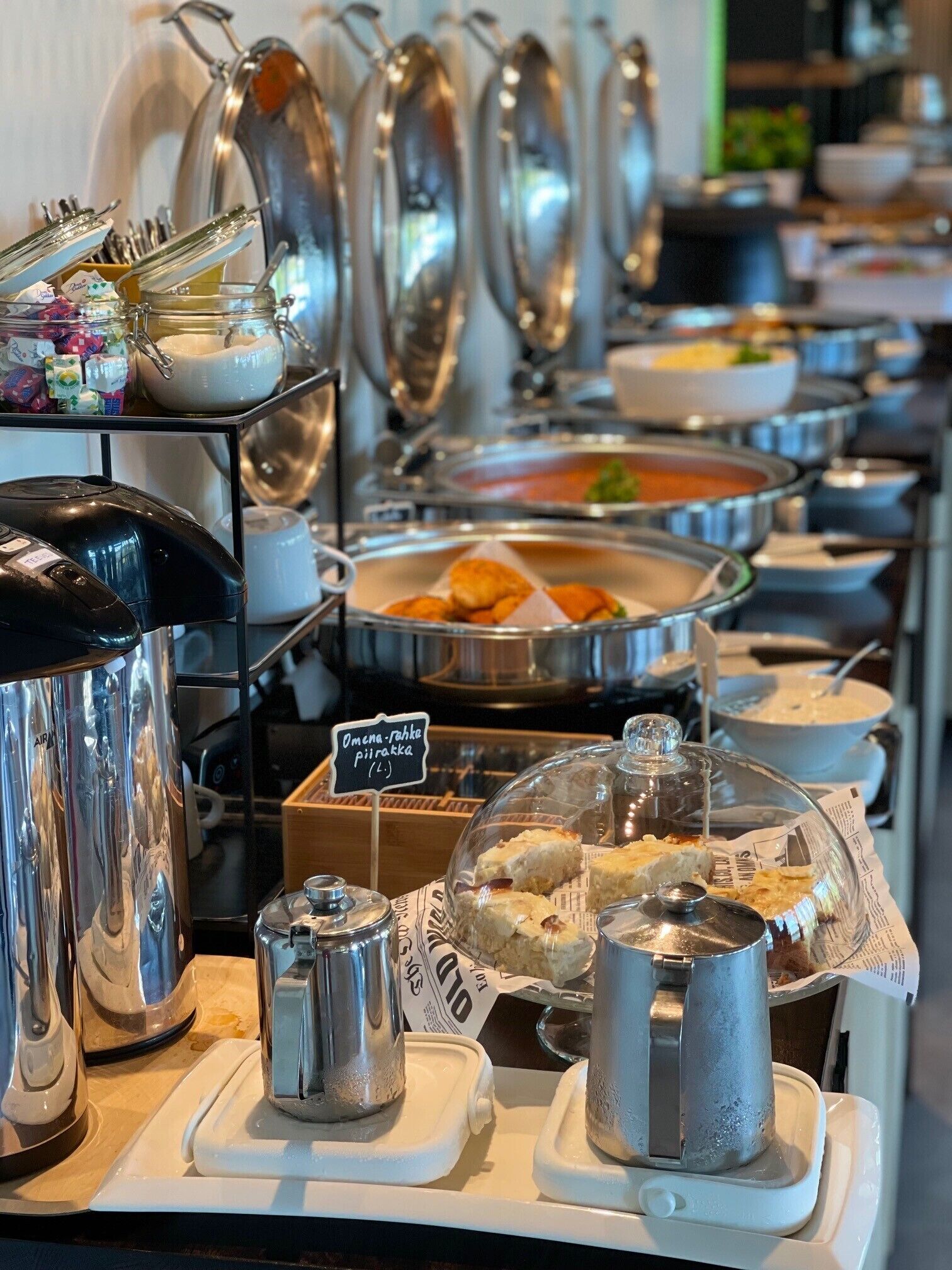 A buffet setup with various food items and serving utensils.
