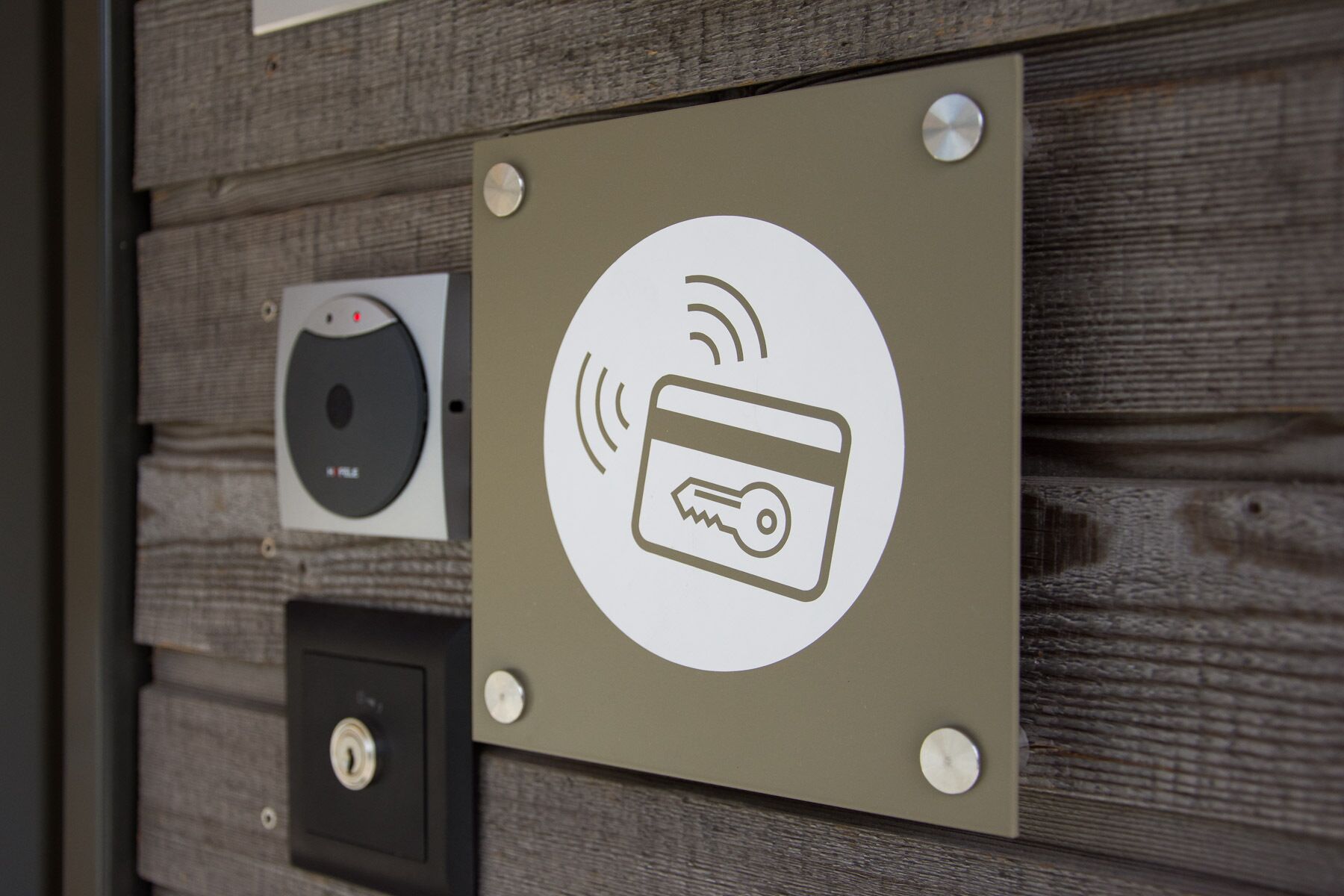 Seinälle kiinnitetty kyltti, jossa on Wi-Fi-symboli ja luottokorttisymboli, jotka ilmaisevat maksutapoja ja mahdollisuuksia muodostaa yhteys verkkoon.