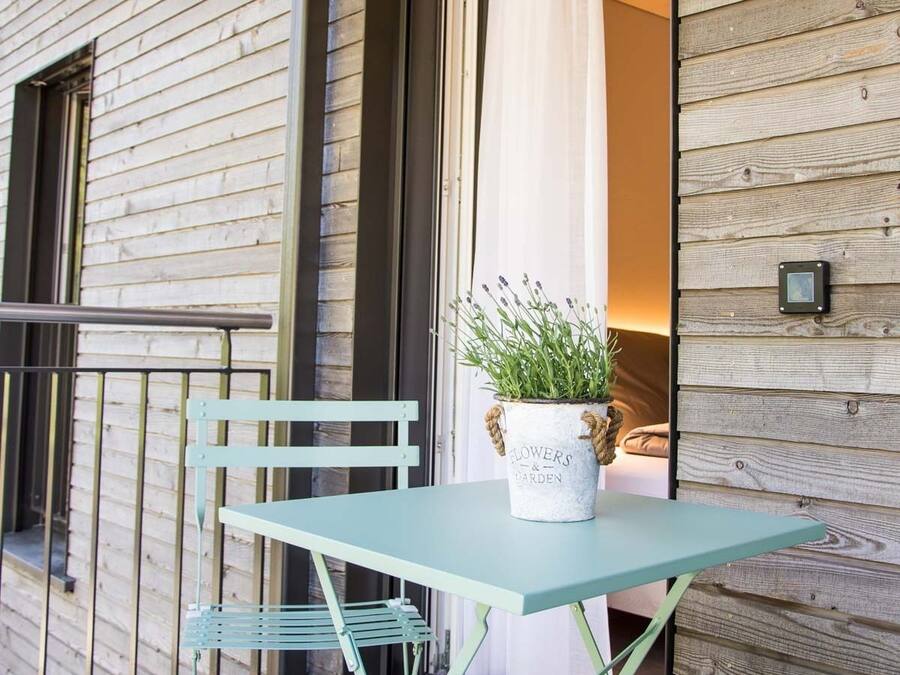 A balcony with a table and chairs, a potted plant, and a wooden wall.