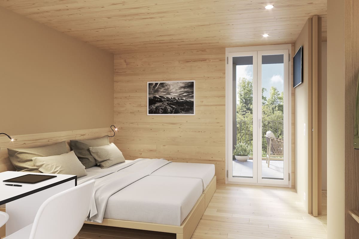 Un dormitorio con cama, mesita de noche y televisor instalado en la pared.