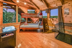 L’intérieur d’une cabane comprend un lit superposé, un téléviseur, une cheminée et une vue sur l’extérieur.