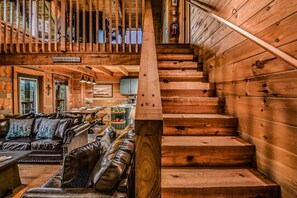 Un intérieur en bois avec un escalier, des canapés en cuir et un coin repas.