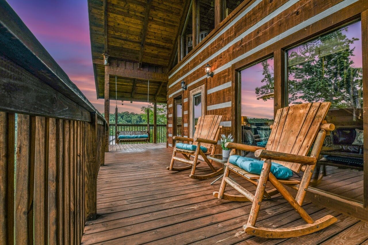 Een houten terras met schommelstoelen en een overdekt gedeelte, met uitzicht op een natuurlandschap.
