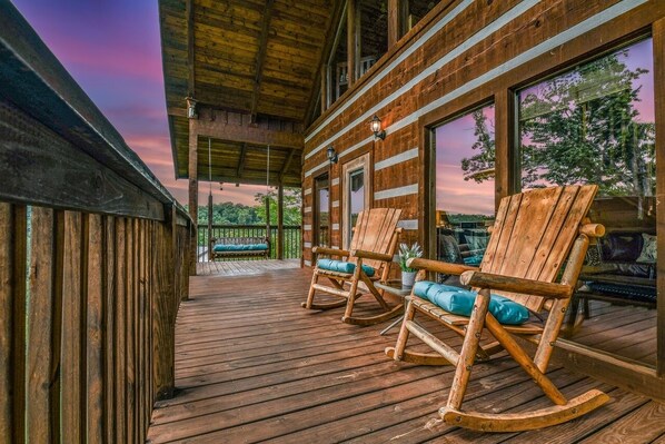 A wooden deck with rocking chairs and a covered area, overlooking a natural landscape. - A-bluff & Beyond 2 Bedroom Cabin by RedAwning (Sevierville)