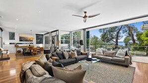 A modern living room with a large sofa, a dining area, and a view of the outdoors. - Seaview House Luxury Coastal Escape Lorne (Lorne)