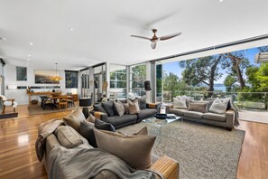 A modern living room with a large sofa, a dining area, and a view of the outdoors. - Seaview House Luxury Coastal Escape Lorne (Lorne)