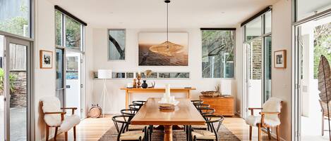 Un comedor moderno con una gran mesa de madera, sillas negras y un tapete con estampado de espiga.