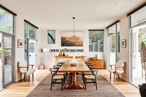 A modern dining room with a large wooden table, black chairs, and a herringbone-patterned rug.