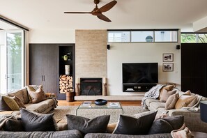 Ein modernes Wohnzimmer mit Kamin, Flachbildfernseher und Deckenventilator.