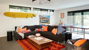 A modern living room with a sofa, coffee table, and a surfboard on the wall. - Seaview House Luxury Coastal Escape Lorne (Lorne)