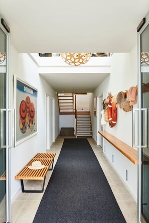 Ein modernes Interieur mit einem zentralen Gang, Holzbanken, einem schwarzen Teppich und einer Treppe.