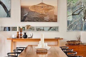 A dining area with a wooden table, black chairs, a woven pendant light, and a wall-mounted shelf with decorative items. - Seaview House Luxury Coastal Escape Lorne (Lorne)