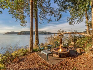A lakeside outdoor seating area with a fire pit, benches, and chairs. - Waterfront! Hot Tub! Dog Friendly! (TSB) (Friday Harbor)