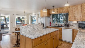 Une cuisine moderne avec des meubles en bois, un plan de travail en marbre et des luminaires suspendus.