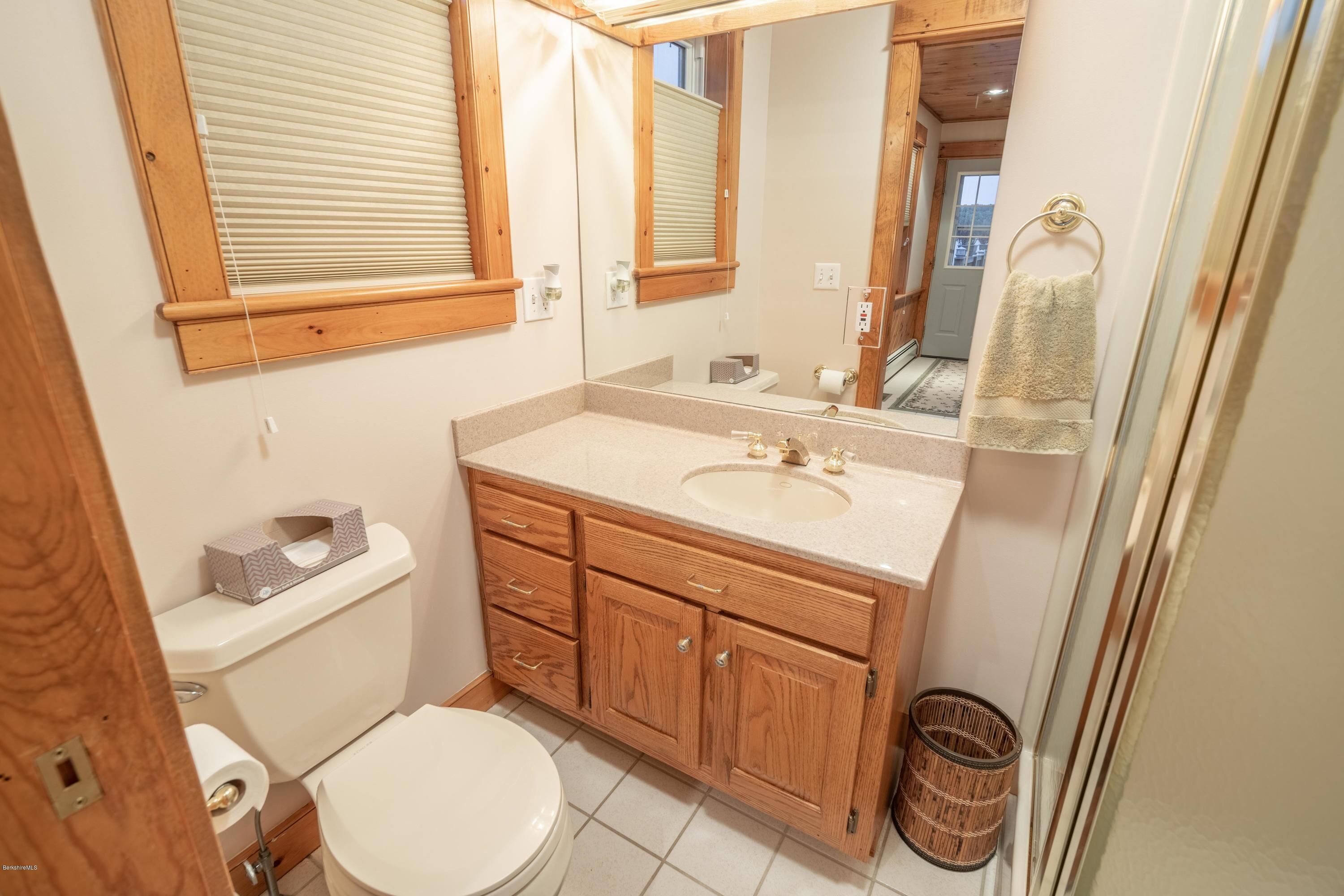 Un baño con tocador de madera, inodoro y espejo.