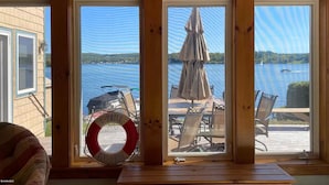 A cabin with large windows overlooking a lake, a U-Drive boat rental sign, and outdoor seating. - Lake Front Home in Heart of the Berkshires Near Jiminy Peak (Pittsfield)