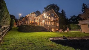 A large, multi-story house with a well-maintained lawn and stone wall. - Lake Front Home in Heart of the Berkshires Near Jiminy Peak (Pittsfield)