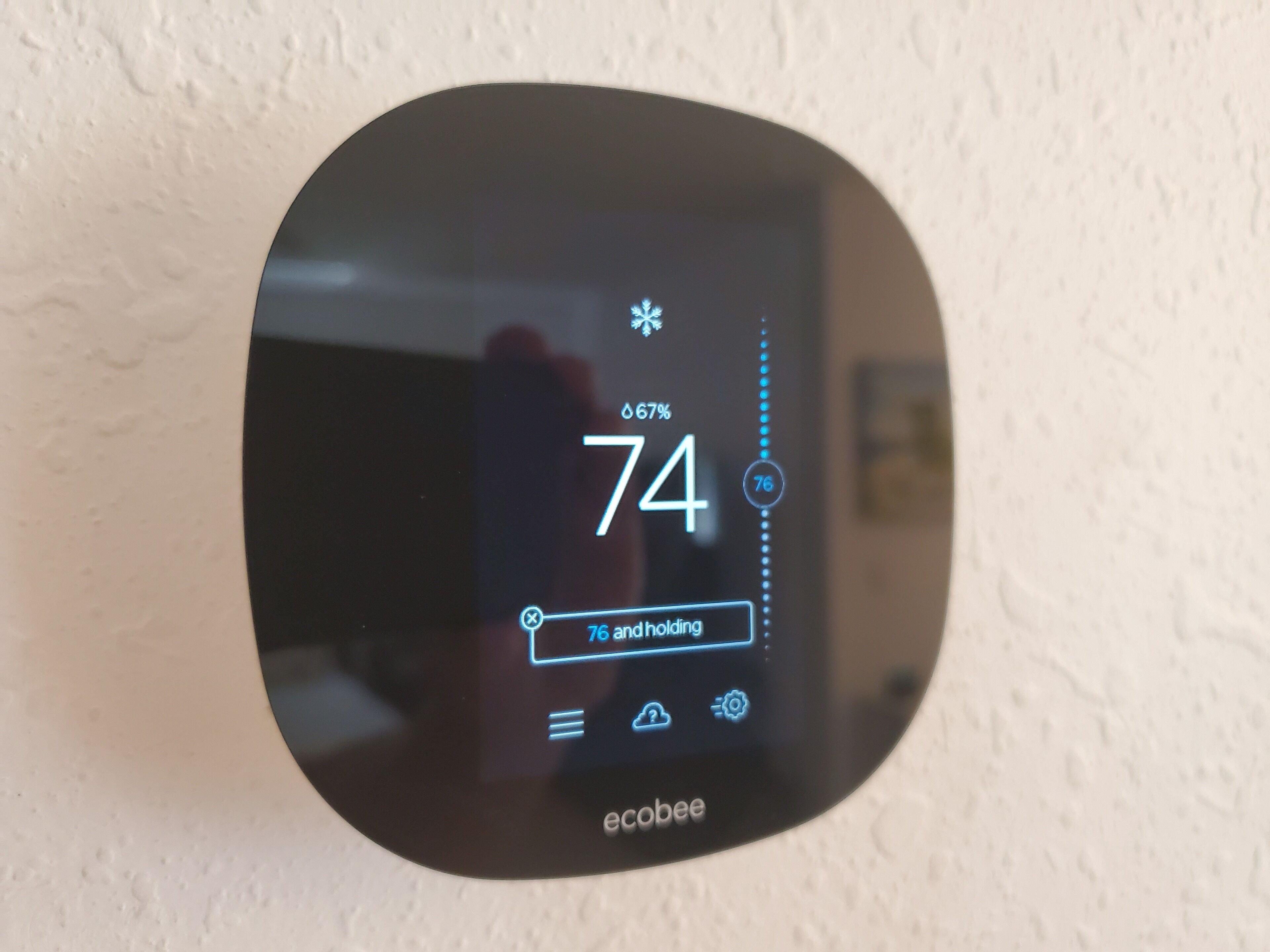 A thermostat displaying a temperature of 74 degrees with a humidity level of 67%.