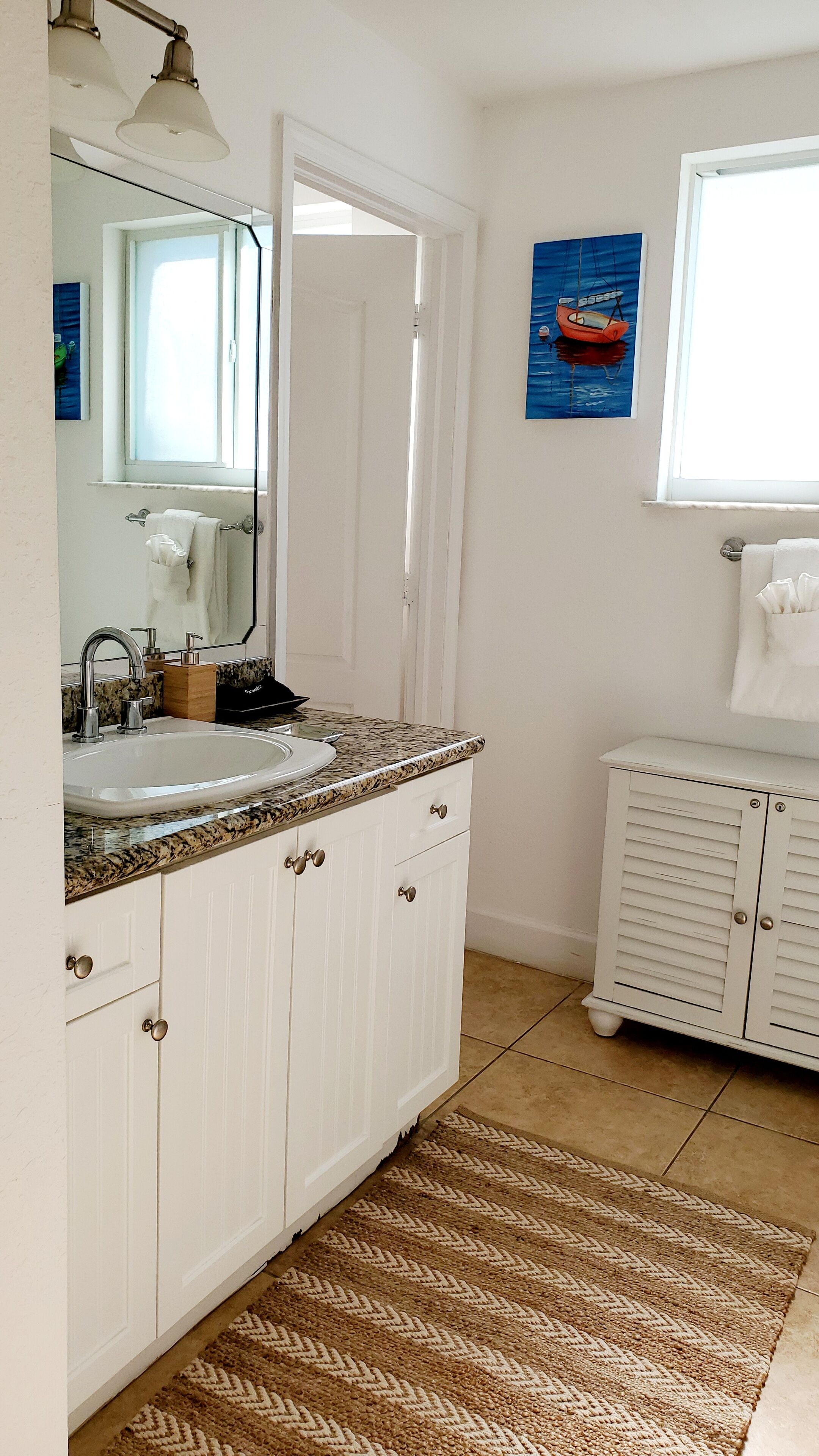 Un bagno con un mobile lavabo bianco, un lavandino e uno specchio.