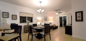 Un espace repas comprenant une table ronde, des chaises, un lustre, des lampes fixées au mur et un ventilateur de plafond.